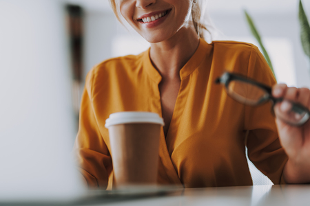 Selective focus of the smiling woman with coffee in front of herの写真素材