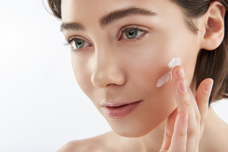 Close up smiling woman with cream on cheekの写真素材