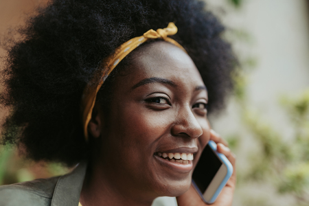 Close up portrait of happy African woman talking on cellphoneの写真素材