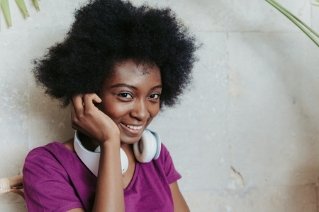 African woman with headphones on shoulders enjoying time in cafe
