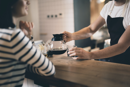 Hands of barista putting coffee jug on the bar counterの写真素材