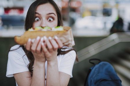 Excited surprised female looking on big hot dogの写真素材