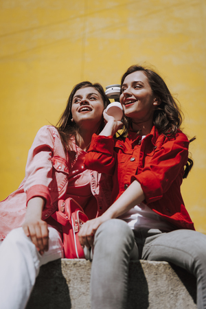 Two hipster girls listen to music on parapetの写真素材