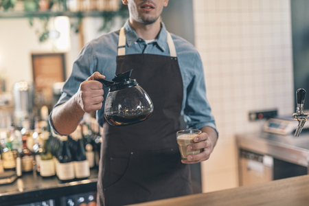 Man at the bar counter with coffee jug and glassの写真素材