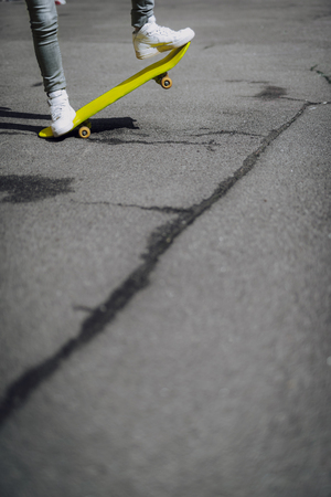 Hipster girl legs balancing on yellow skateboardの写真素材