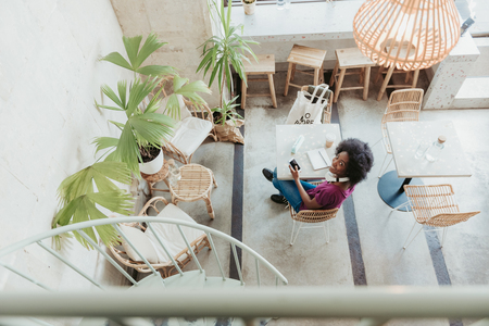 High angle of African woman sitting at table with gadget in armの写真素材