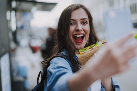 Happy female making selfie with fast foodの写真素材