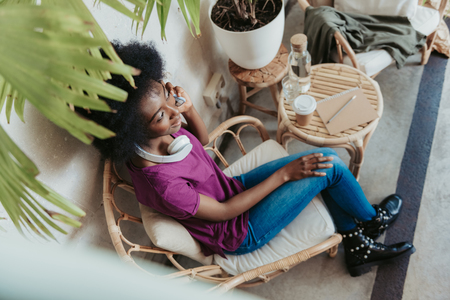 High angle of African woman wearing casual and talking on smartphoneの写真素材