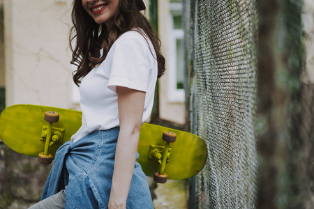 Young trendy hipster girl with yellow skateboardの写真素材