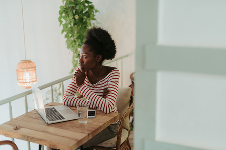 Half length of calm African woman sitting at table in cafeの写真素材