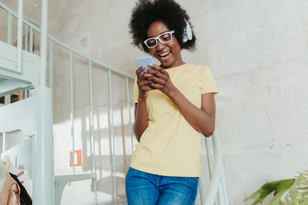Half length of African lady wearing casual and keeping cellphone in armsの写真素材