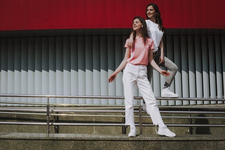 Pretty hipster girls posing on city parapet