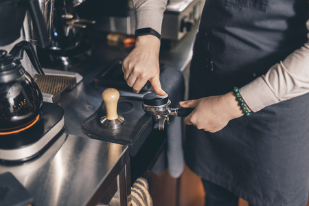 Barista making coffee pod in filter holder with round tamperの写真素材