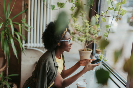 High angle of happy African lady looking through window in cafeの写真素材