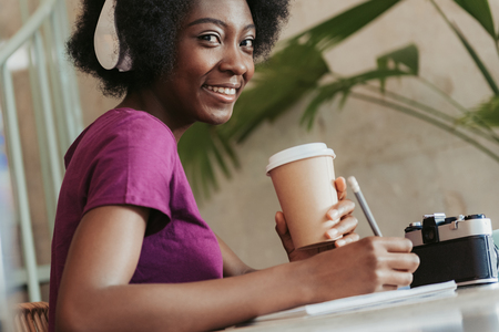 Close up of African woman with curly hair keeping cupholder in armsの写真素材