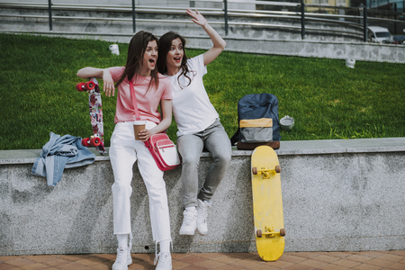 Two pretty skater girls having coffee breakの写真素材