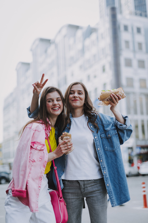 Happy females making funny photo with hot dogsの写真素材