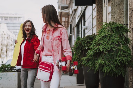 Two happy hipster girls walking with skateboardsの写真素材
