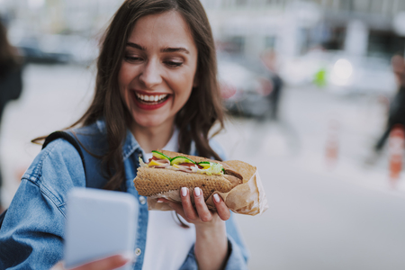 Joyful female making selfie with hot dogの写真素材