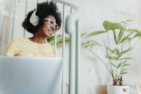 Cropped photo of happy African lady wearing headphones and working on computer