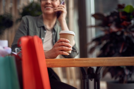 Careful stylish woman talking by phone in cafeの写真素材