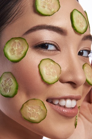 Face with cucumber slices close up photo of womanの写真素材