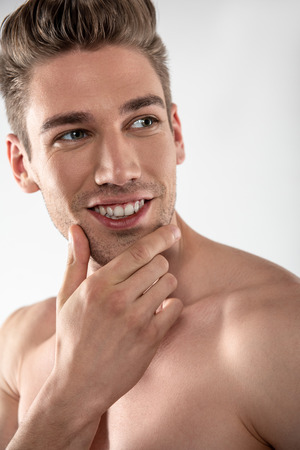 Attractive young man with stylish haircut touching his faceの写真素材