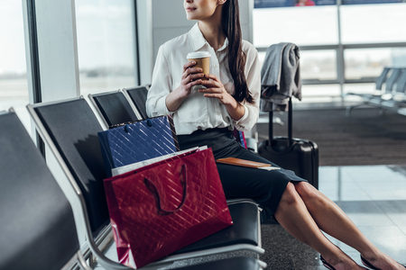 Tranquil woman is waiting for plane with hot drinkの写真素材