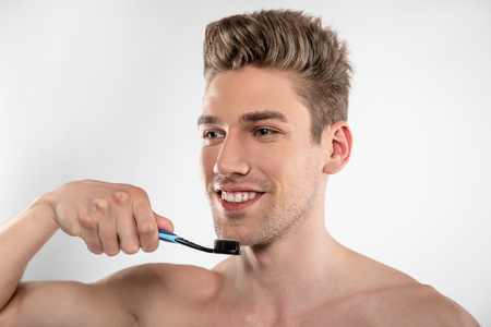 Handsome young man with stubble holding toothbrushの写真素材