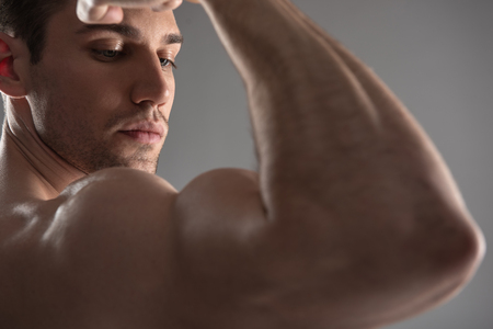 Handsome young man demonstrating his muscular strong armの写真素材