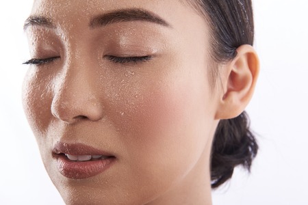 Close up of wet face of young Asian womanの写真素材