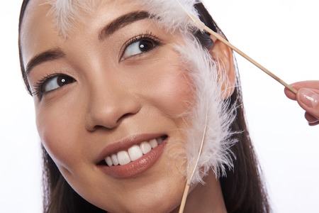 Asian woman and soft feathers touching her skinの写真素材