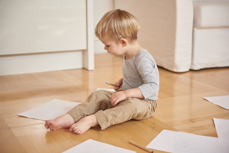 Adorable little boy drawing with colored pencil at homeの写真素材