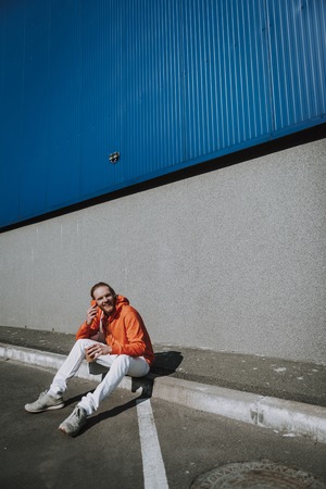 Happy hipster man talking by phone on streetの写真素材