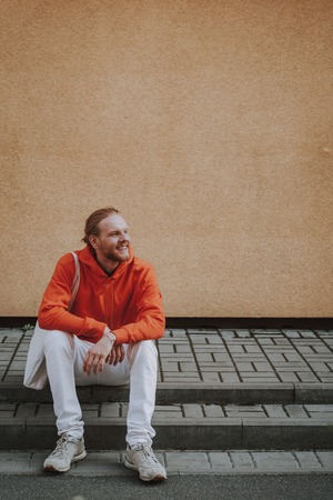 Happy smiling hipster man sitting on stairsの写真素材