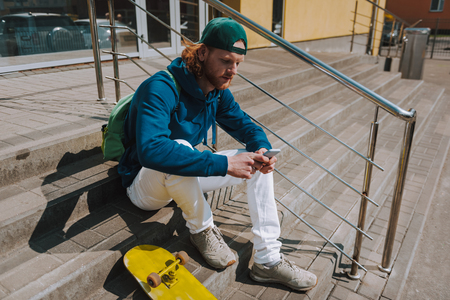 Skater man messaging on mobile phone on stairsの写真素材