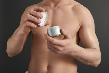 Close up of Caucasian guy opening jar of hair gel in studioの写真素材