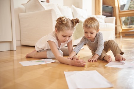 Adorable children drawing with colored pencils at homeの写真素材