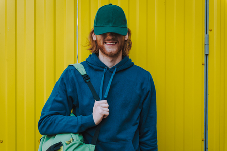 Happy young hipster man on yellow fence viewの写真素材