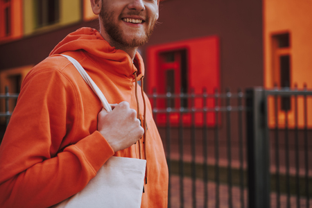 Young smiling man with eco bag on walkの写真素材