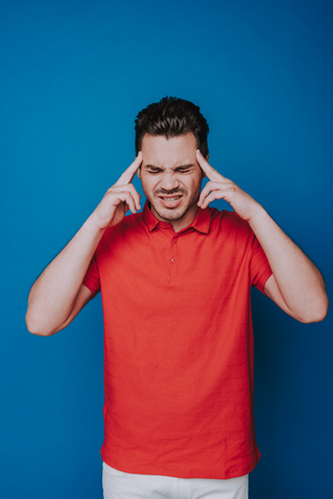 Half length of Caucasian man trying to concentrate isolated on blue backgroundの写真素材