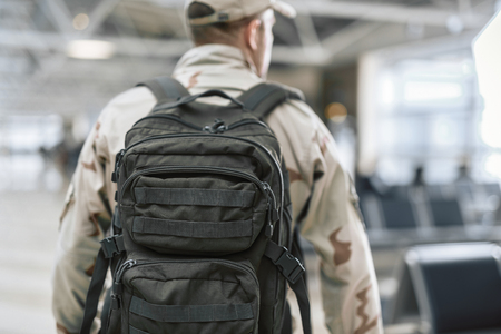 Cropped photo of American soldier in camouflage holding rucksack on backの写真素材