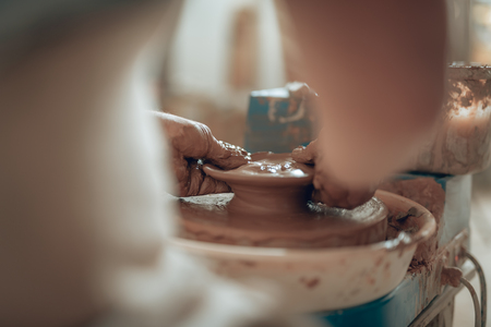 Close up of clay masters dirty arms working on potters wheelの写真素材