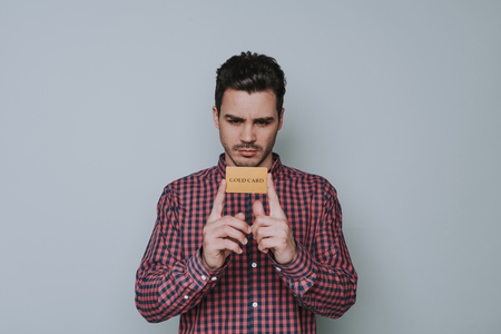 Half length of handsome serious guy holding gold card in armsの写真素材