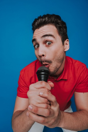 Half length of unshaven guy looking at camera with microphone in arm
