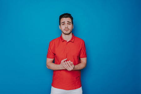 Half length of sad man keeping his palms together indoorsの写真素材