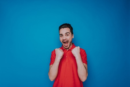 Half length of smiling bearded guy looking at camera and saying hurrayの写真素材