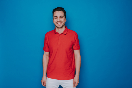 Half length of smiling Caucasian man looking at camera against blue wallの写真素材