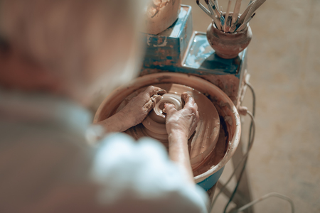 Back view of female potter modeling clay decorative product in workshopの写真素材