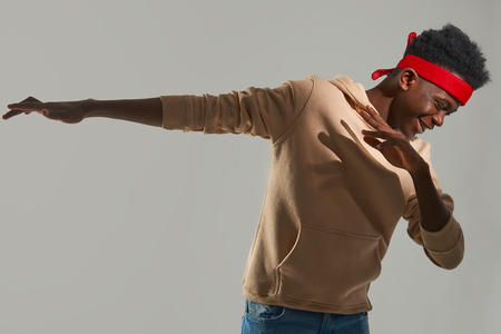 Cheerful Afro American man with red headband dancing on white backgroundの写真素材